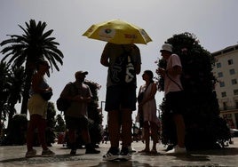 Varias personas intentan mitigar el impacto del sol en Málaga.