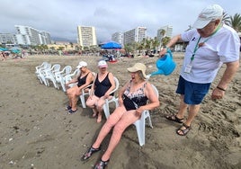 Mercedes y María, en primer plano, se refrescan sentadas frente al mar.