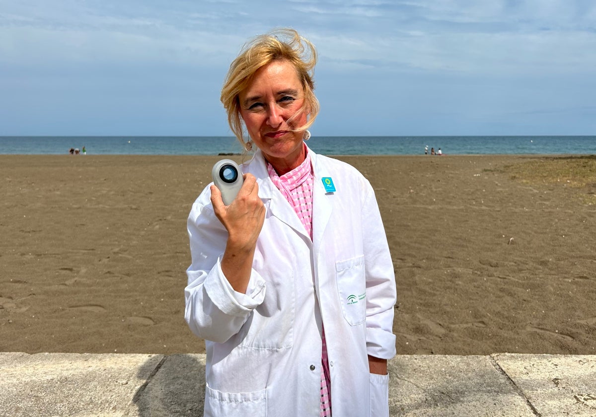 Magdalena de Troya posa con su bata, el pin de Soludable y un dermatoscopio en la playa de la Misericordia.