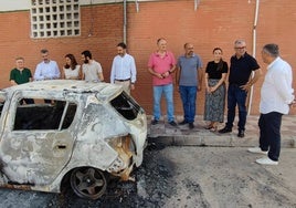 Ediles, alcaldes y dirigentes socialistas, este miércoles en Periana junto al coche incendiado.