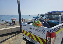 Un vehículo de la Policía Local, con enseres retirados de la primera línea de playa.