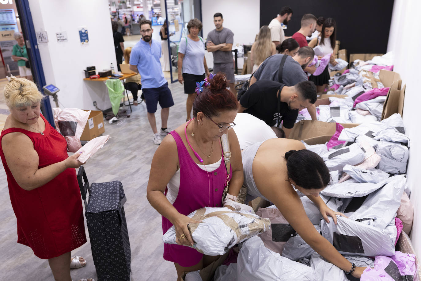 Clientes buscan entre la montaña de paquetes.