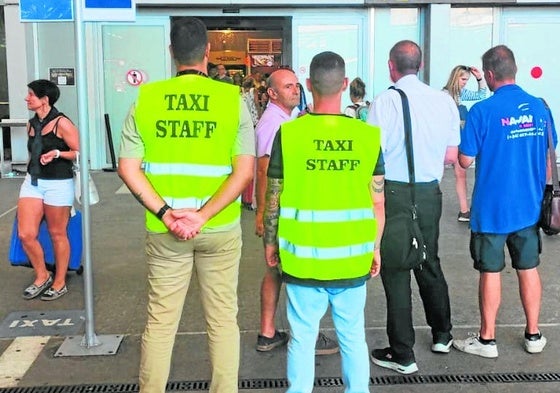 Dos taxistas vigilan que la terminal de salidas para impedir que los piratas capten a turistas.