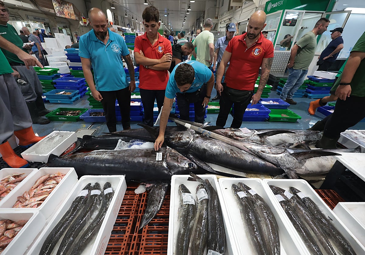 Un grupo de mayoristas contempla el género antes de que se abran las puertas a los minoristas, a las cinco de la mañana