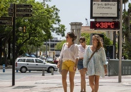 Jóvenes pasean por la plaza de la marina de Málaga, bajo un termómetro que marca 38 grados.