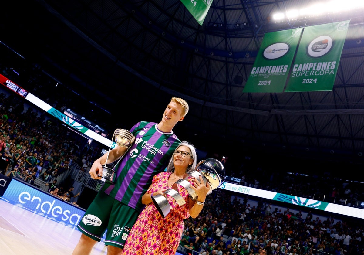 Alberto Díaz y Toñi García posan con los trofeos y las banderas detrás.