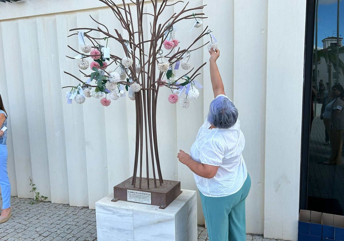 Una mujer pone una flor en el Árbol de las Ausencias.