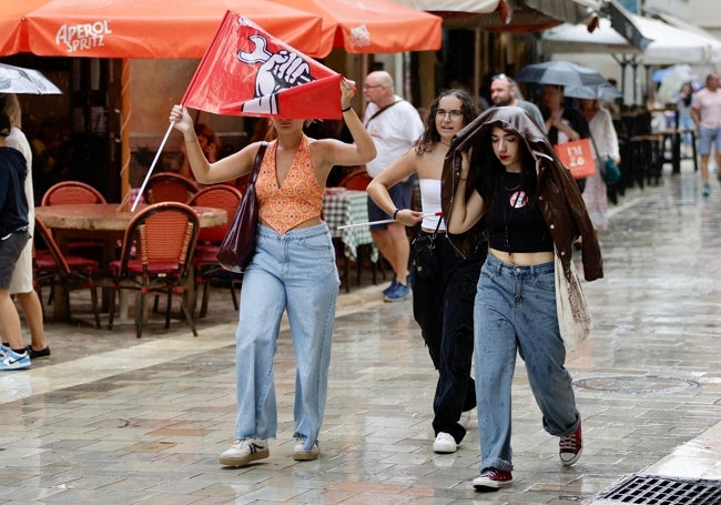 Tres jóvenes se refugian de la lluvia, tras participar en la manifestación de estudiantes.