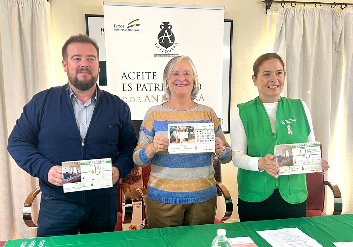 Benito Avilés de la DOP Aceite de Antequera, y Susana Leruite y Ana Pérez de la AECC con el calendario benéfico del año 2025