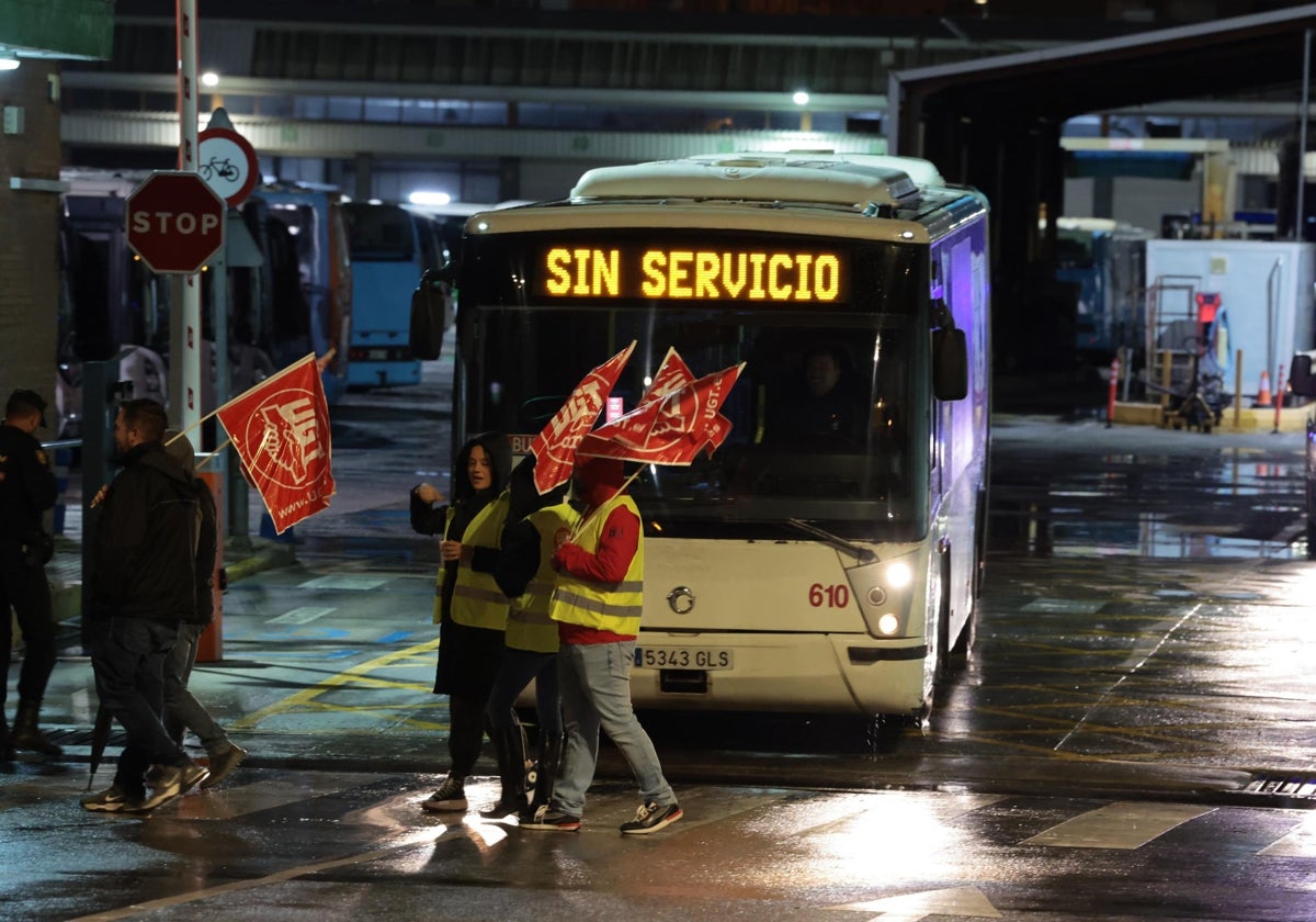 Sindicalistas pasan frente a un autobús en las cocheras de la EMT.