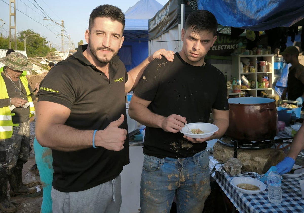 Álvaro Faura, de 30 años, a la izquierda, en la carpa instalada por él en Paiporta para cocinar a los vecinos.