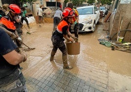 Una de las voluntarias de Protección Civil de Rincón de la Victoria retira barro de las calles.