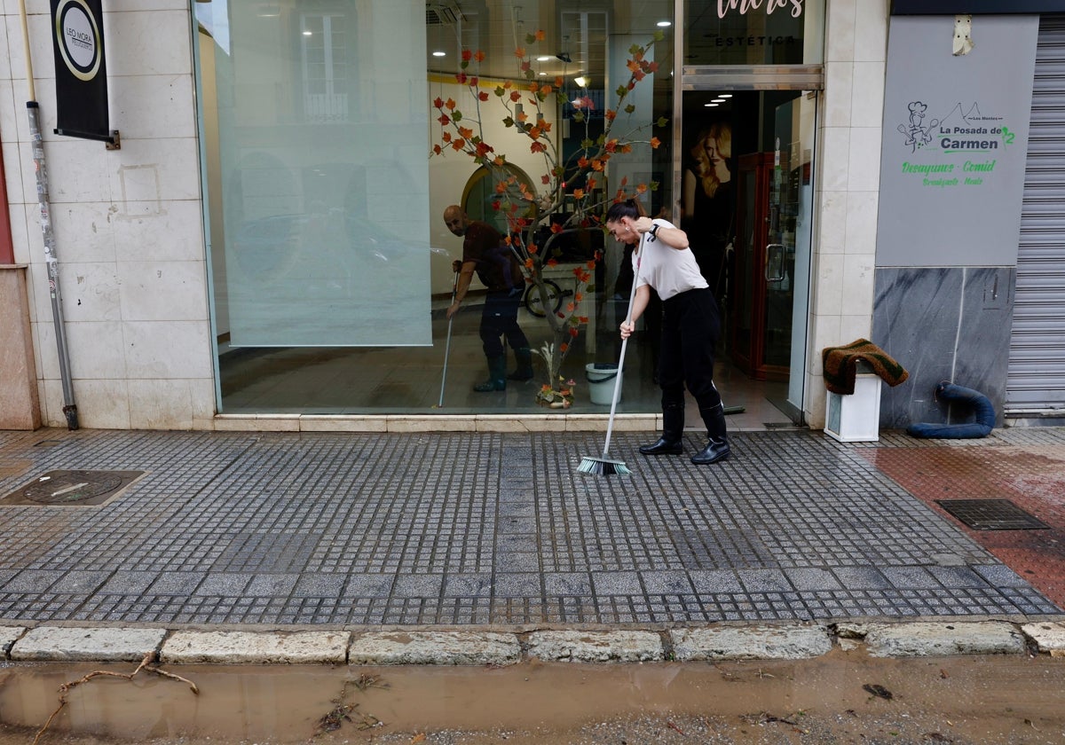 Una trabajadora limpia la acera de delante de su local en el Centro de Málaga.