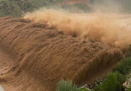 Imagen del torrente desbordado por encima de la berma de la presa de derivación del Mazmúllar en Comares, en el cauce del río Solano.