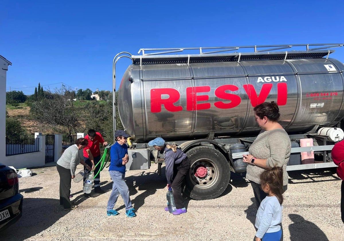 Vecinos de Comares llenan botellas de agua de uno de los camiones.