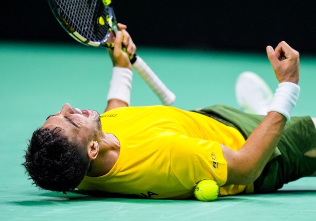 Thanasi Kokkinakis celebra exultante su victoria desde el suelo.