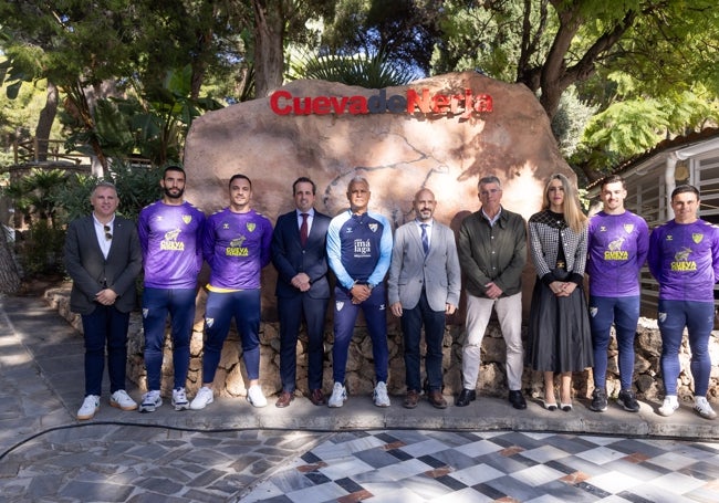 El Málaga posa en frente de la entrada de la Cueva de Nerja, junto con varios representantes de la Fundación Pública de Servicios Cueva de Nerja.