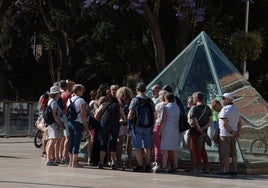 Turistas atienden las explicaciones de la guía en calle Alcazabilla.