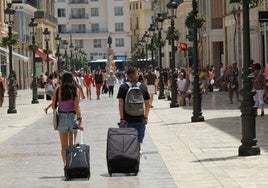 Turistas avanzan por calle Larios camino de su alojamiento.