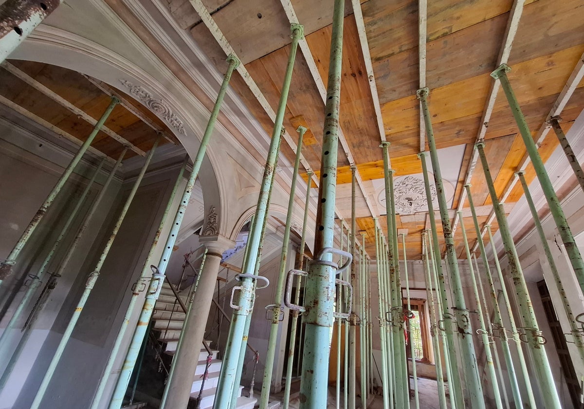 Imagen principal - Las columnas del zaguán están casi ocultas por los puntuales de obra, colocados para mantener firme la estructura del edificio, donde hay partes del suelo que ya han cedido y, a duras penas, se mantiene la decoración original.