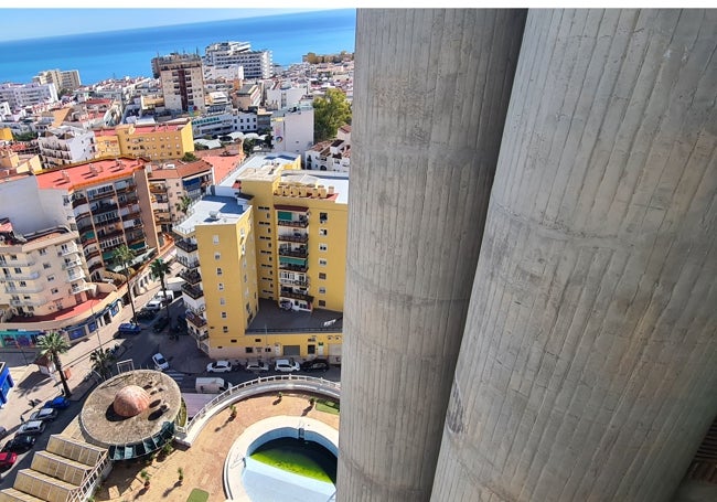 Vista lateral de los cilindros exteriores de las torres, sobre la piscina del Conjunto Los Manantiales y la cubierta del hotel; la plaza Costa del Sol, en segundo término, y, al fondo, la línea de la costa.