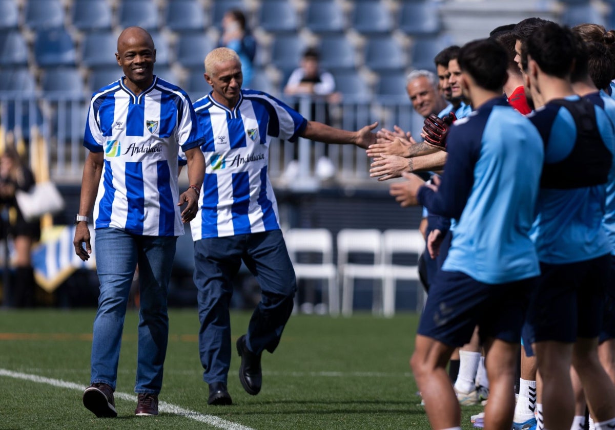 Dely Valdés y Darío Silva lucen la nueva camiseta retro del Málaga en La Rosaleda.