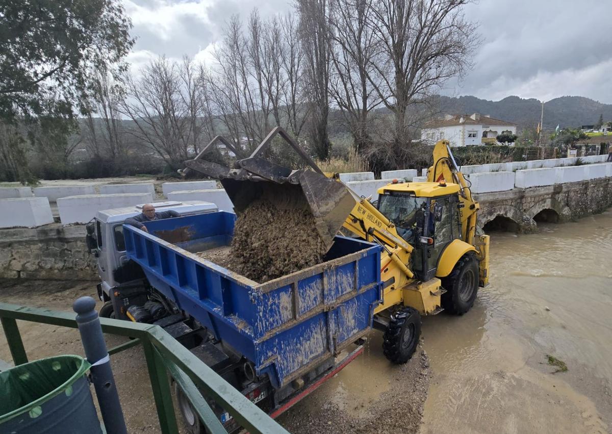 Imagen secundaria 1 - Trabajadores en el polideportivo, Juan Manuel García, limpiando con su máquina el barro y su padre, en la parcela de su hijo.