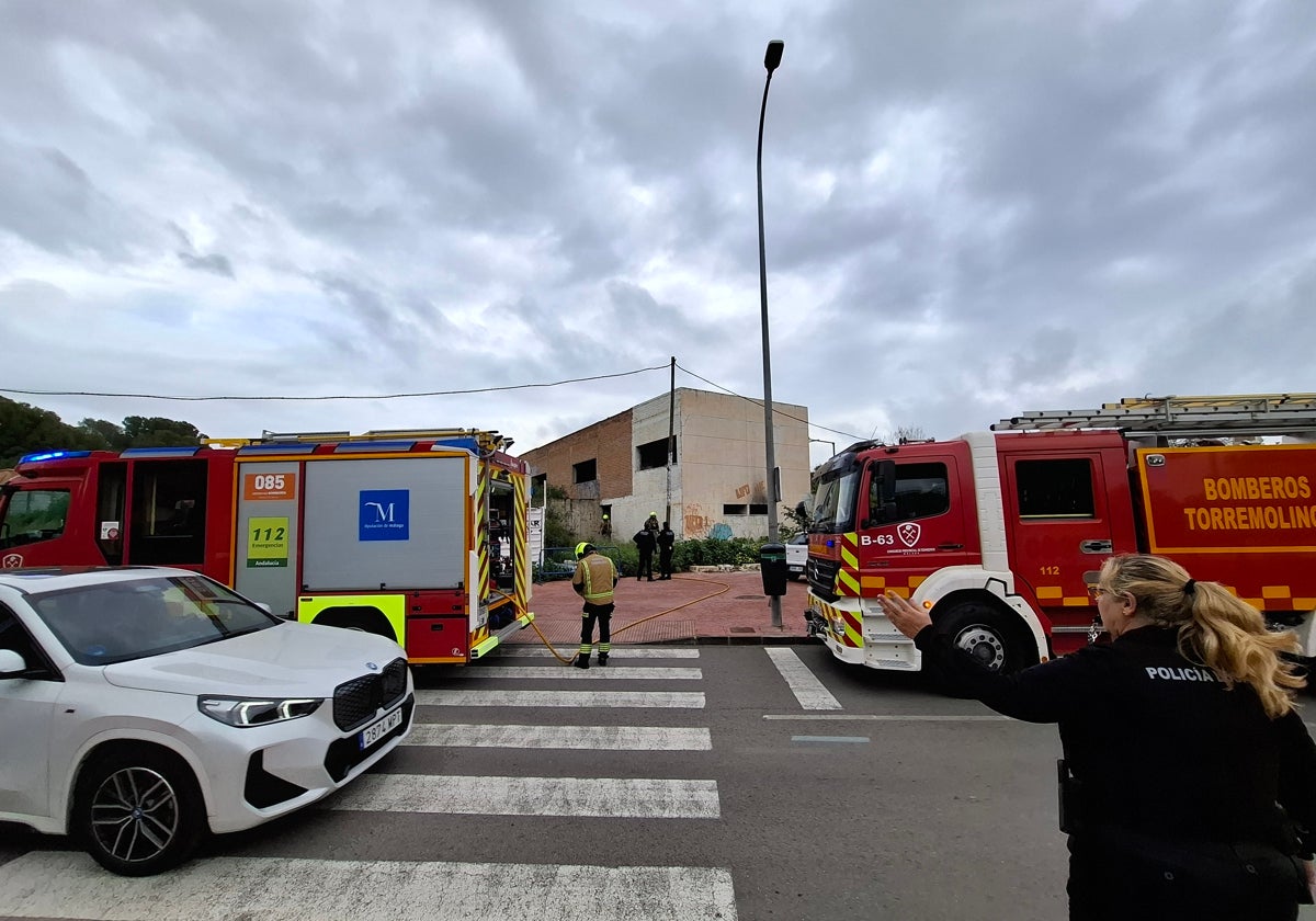 Una policía local regula el tráfico en la calle Ecuador, mientras compañeros suyos y bomberos se despliegan en la zona afectada por el fuego.