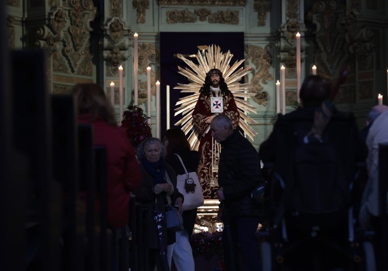 Varios devotos frente al Cristo de Medinaceli tras depositas las tres monedas.