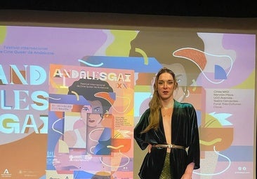 Lola Buzón, actriz, activista LGTBI y jurado de esta edición de Andalesgai, junto al cartel del Festival.