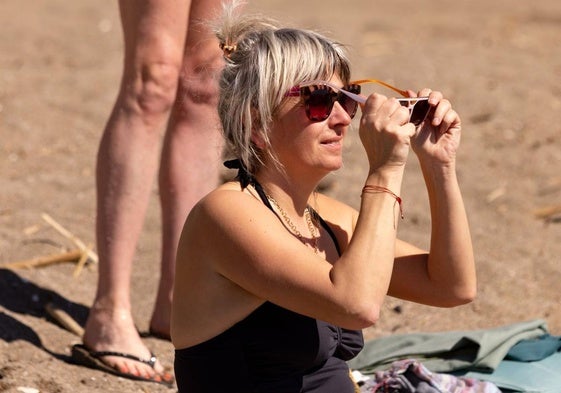 Varias personas contemplan el eclipse parcial de este sábado, desde la playa de La Malagueta.