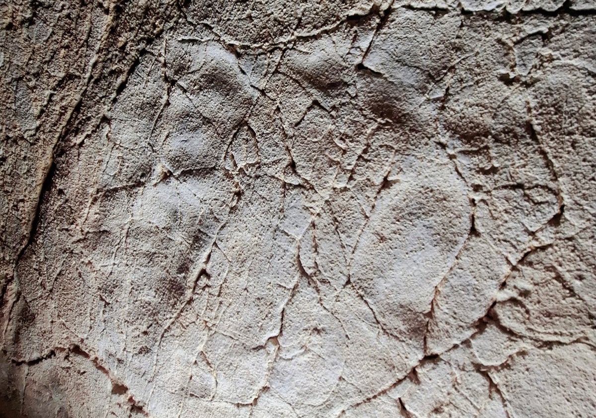Imagen principal - Una marca de mano; el alcalde de Ardales, con el concejal de Cuevas y el regidor de Rincón de la Victoria, y el equipo de investigadores, y líneas marcadas con los dedos en una de las paredes.