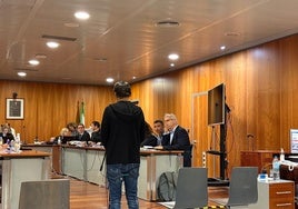El principal acusado, sentado el segundo por la derecha y otro de los procesados, de espaldas y declarando.