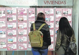Dos chicas observan el escaparate de una agencia inmobiliaria.