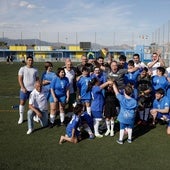 Los niños de Espíritu Deportivo y algunas leyendas del Málaga levantan el trofeo conmemorativo en el campo de la Unión Deportiva Dos Hermanas-San Andrés.