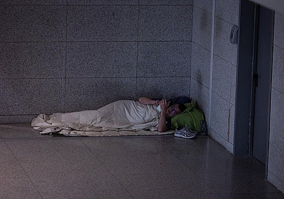 Persona sintecho acostada en un rincón de la T3 del aeropuerto de Málaga.