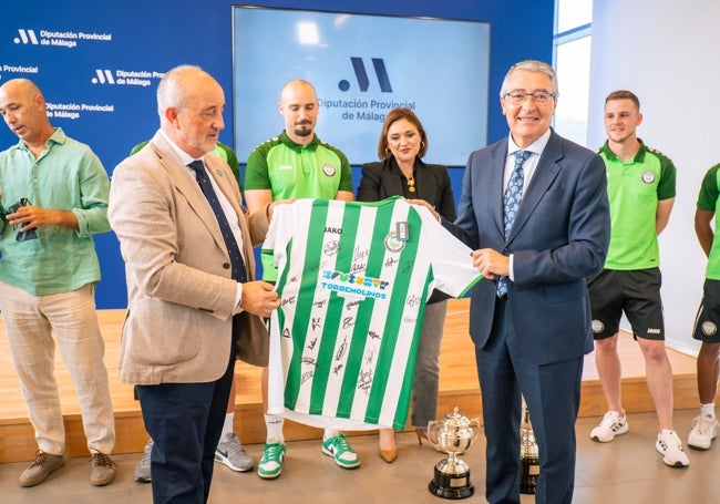 Juan Espárraga, presidente del Torremolinos, y Francisco Salado, presidente de la Diputación de Málaga, posan con la camiseta del Torremolinos, firmada por los artífices del ascenso a Primera RFEF.