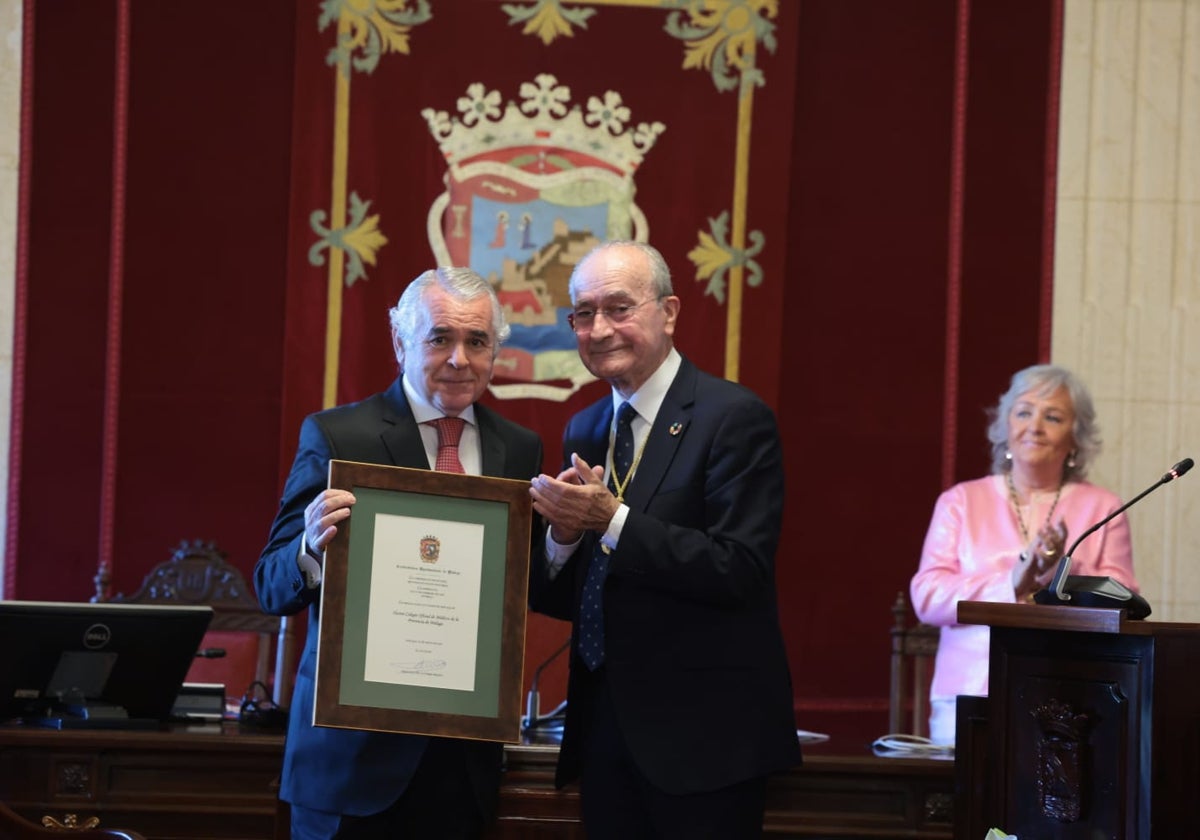 Pedro Navarro, presidente del Colegio de Médicos, recibe el nombramiento de Hijo Predilecto de manos del alcalde. Al fondo, la edil Teresa Porras, instructora del expediente, aplaude.