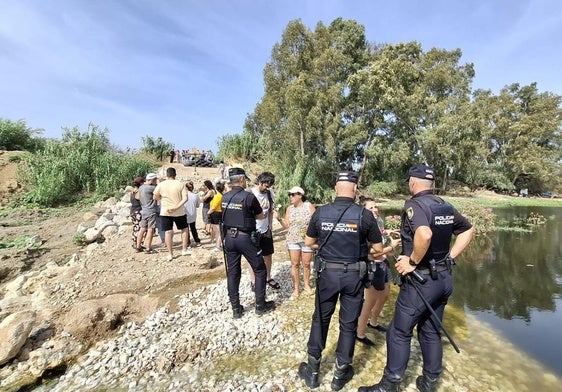 Policías y vecinos, apostado junto al río.