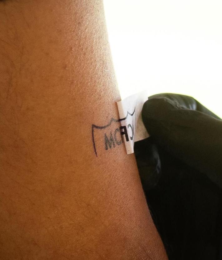 Imagen secundaria 2 - Un aficionado del Málaga se tatúa la fecha del ascenso (22/06/24) debajo del escudo, a manos del tatuador Pedro. Dos aficionados muestran sus tatuajes. Detalle de uno de ellos.