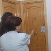 Una vecina señala la puerta de la vivienda de la víctima, precintada por la Policía.