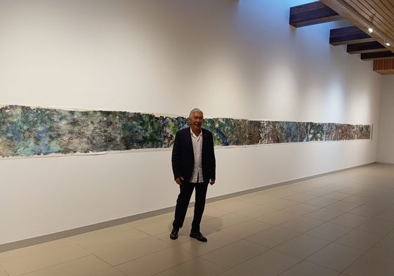El autor posa con su pintura de 18 metros.