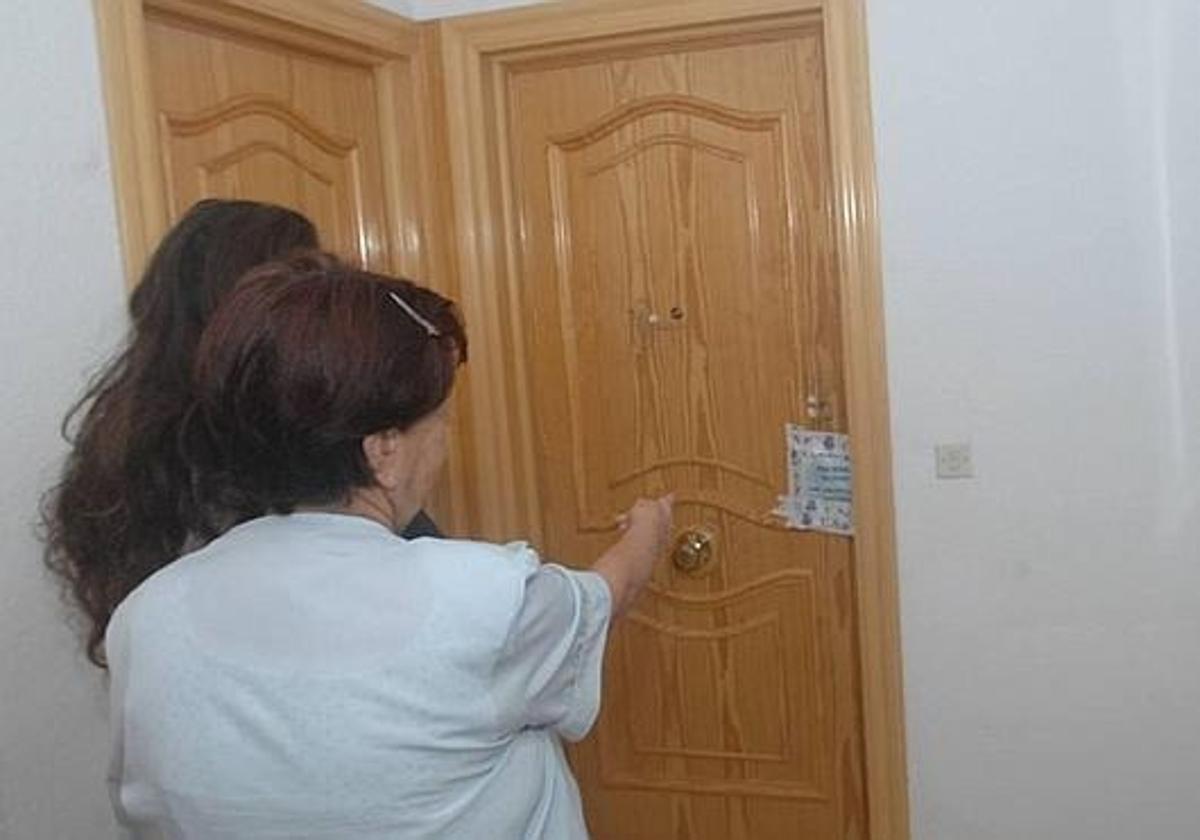 Imagen de archivo de una vecina señalando la puerta de la vivienda de la víctima, precintada por la Policía.