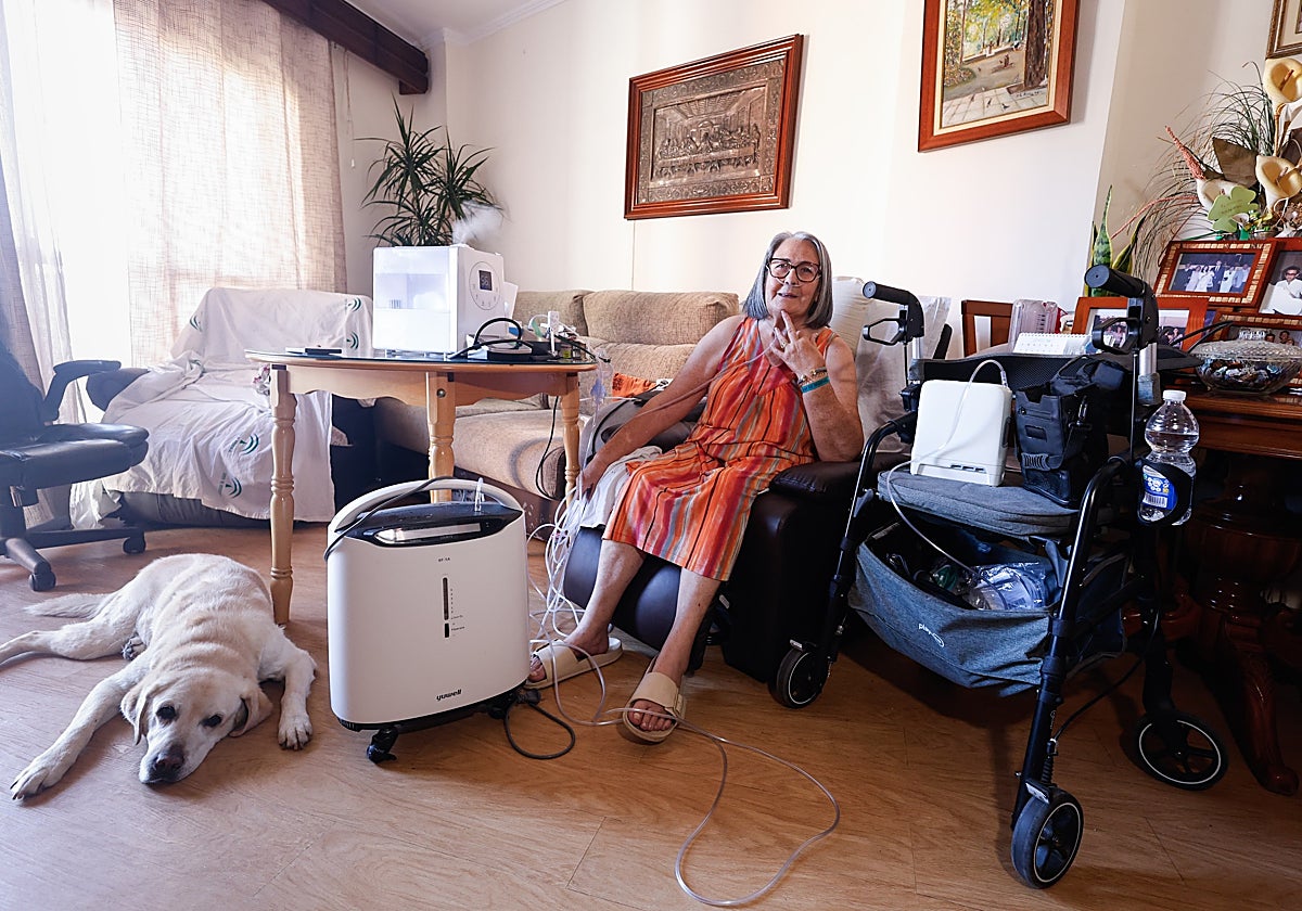 Imagen de Carmen Núñez Manchado, en el salón de casa, junto a su perra Lola.