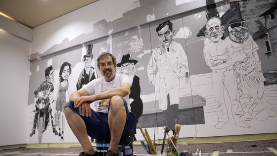 Ángel Idígoras, sentado sobre los botes de pintura, con los primeros personajes de su nuevo mural cinéfilo.