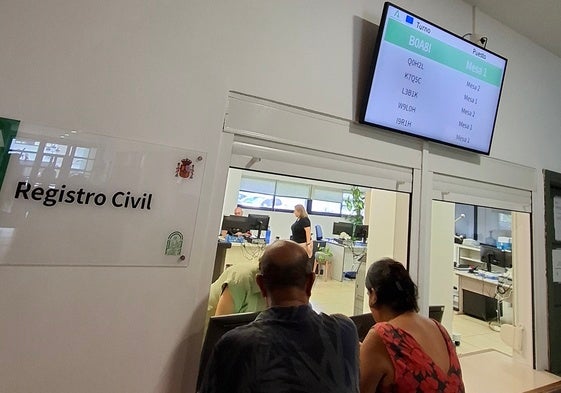 Dos usuarios esperan a ser atendidos en el Registro Civil.