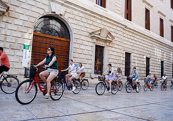 Un grupo de visitantes recorre el Centro de la ciudad en bicicleta.