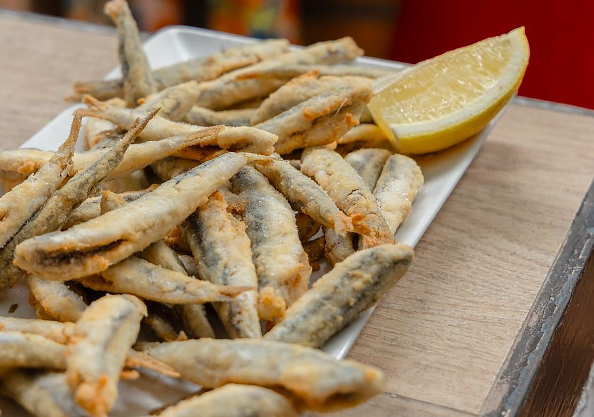 Imagen principal - Arriba, el 'pescaíto' frito no puede faltar estos días. Abajo, a la izquierda, pocos establecimientos se resisten a incluir el jamón en su carta. A la derecha, las gambas, otro de los platos que más se ven en las mesas.
