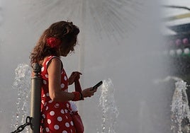 Una asistente al real de la feria busca el frescor de las fuentes para descansar.