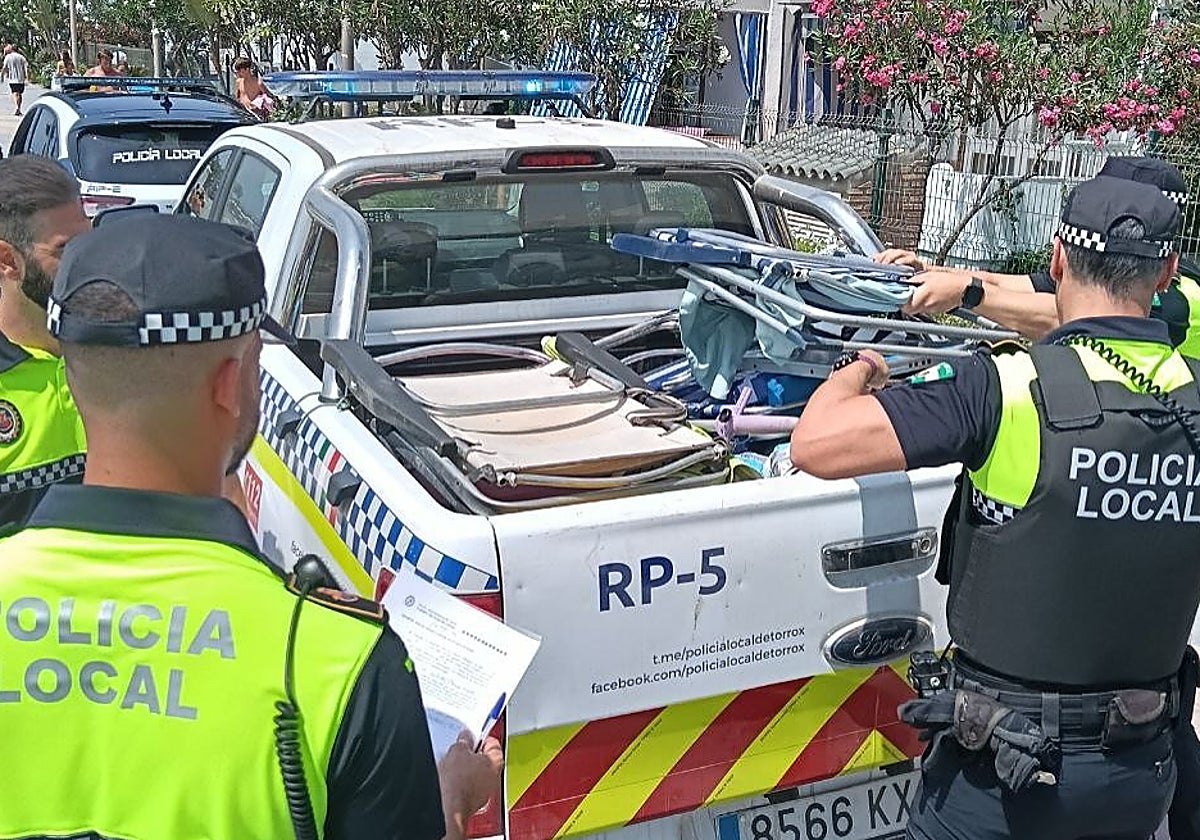 Agentes de la Policía Local, en una actuación contra las ocupaciones de playa en primera línea con sillas y sombrillas.